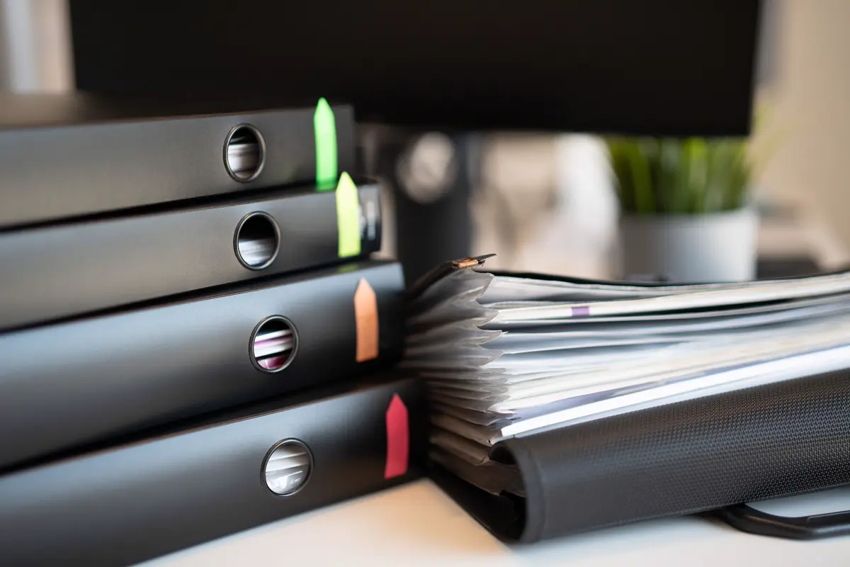 Black ring binders and an open folder holding organized documents